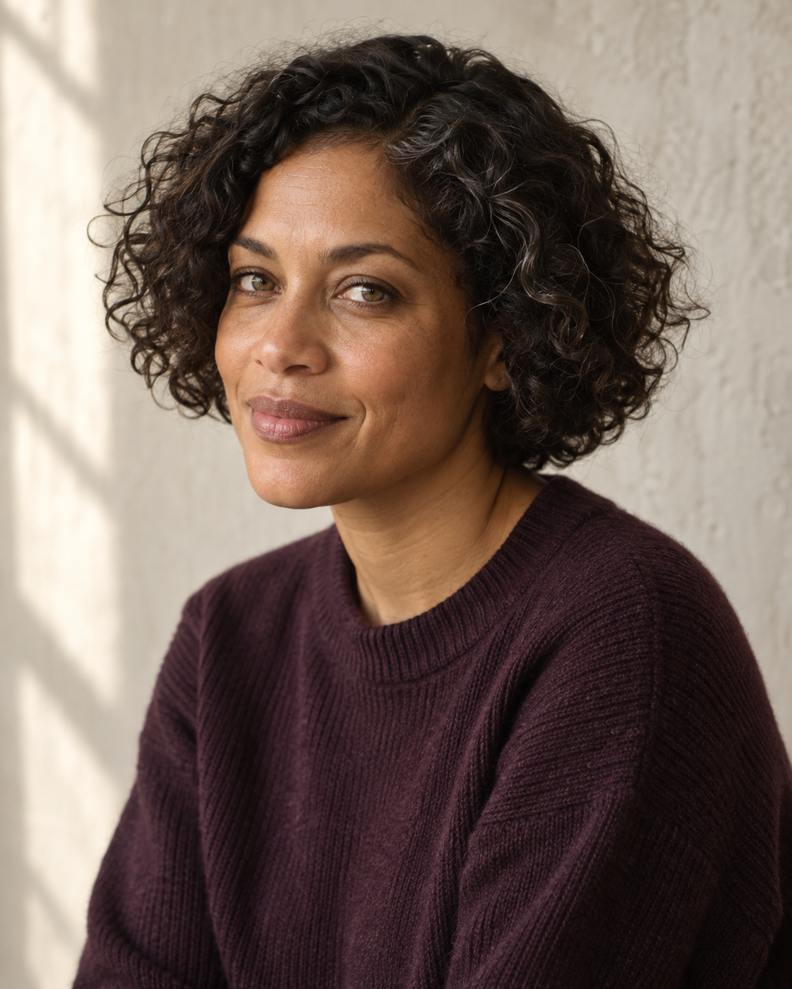 Illustrative portrait of Nia Mercer with short dark curls and an aubergine knit